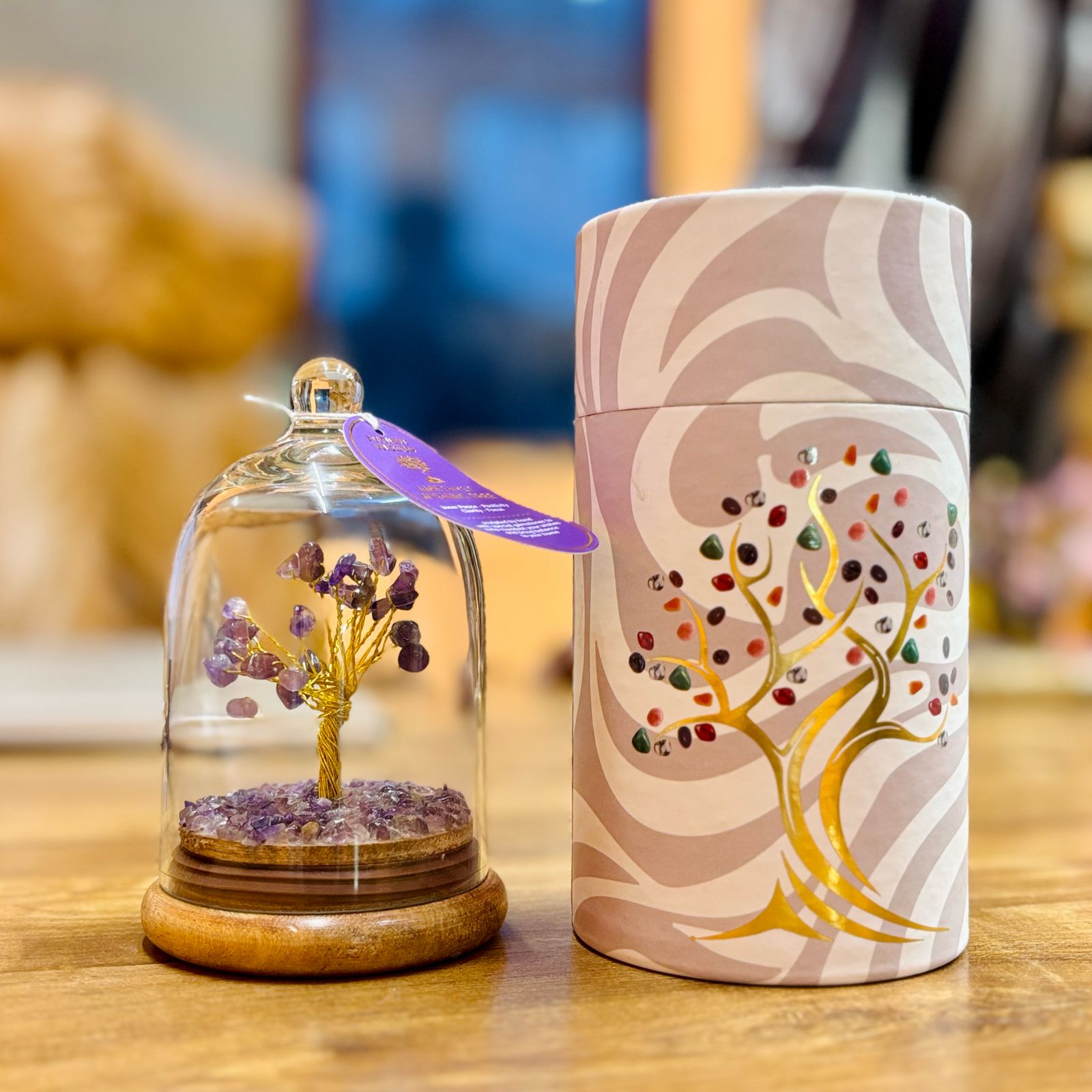 Small glass dome containing a Amethyst gemstone tree with gold trunk with Amethyst chips scattered on the ground.