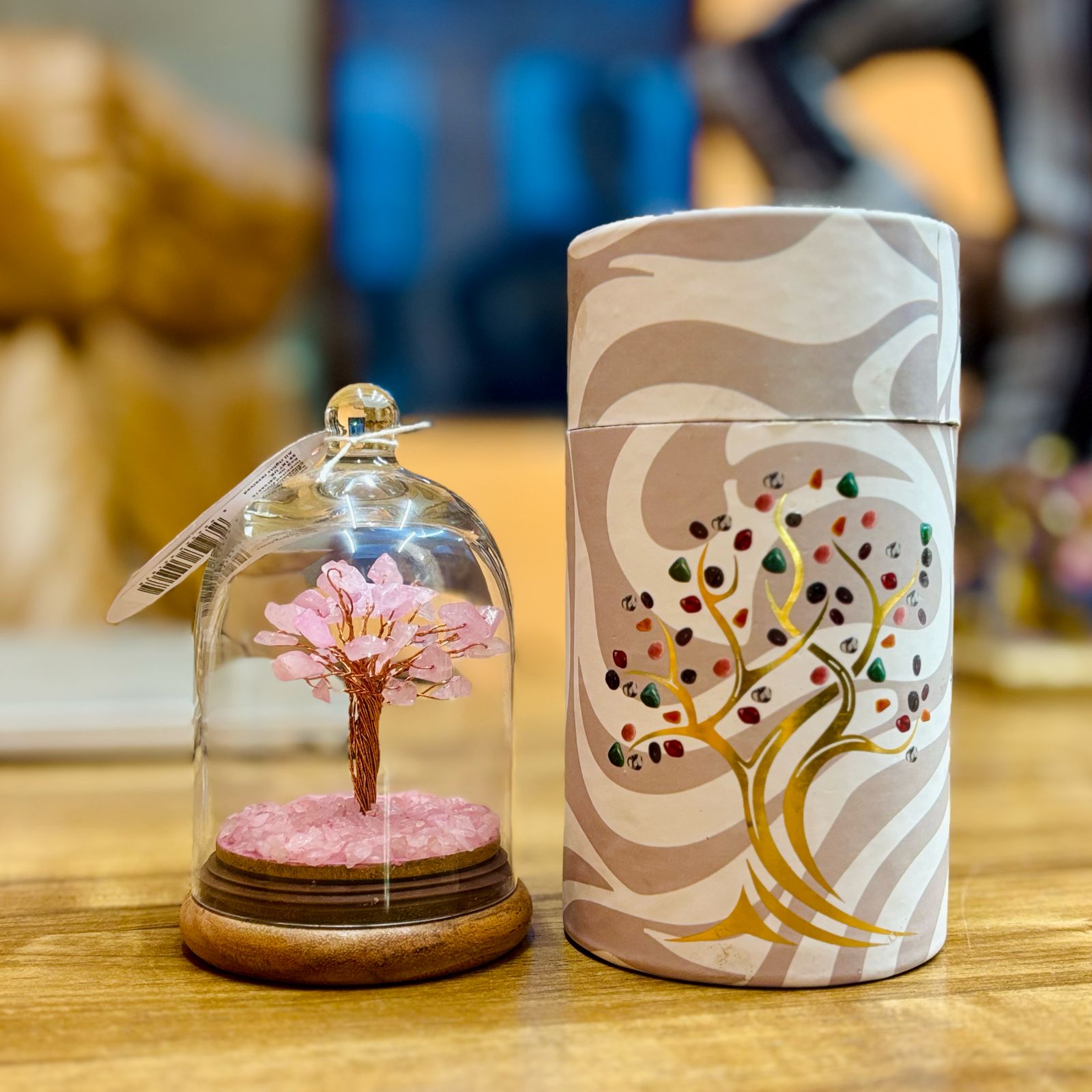 Small glass dome containing a Rose Quartz gemstone tree with copper trunk with Rose Quartz chips scattered on the ground.