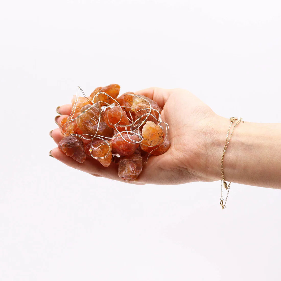 Hand holding a cluster of amber stones against a white background