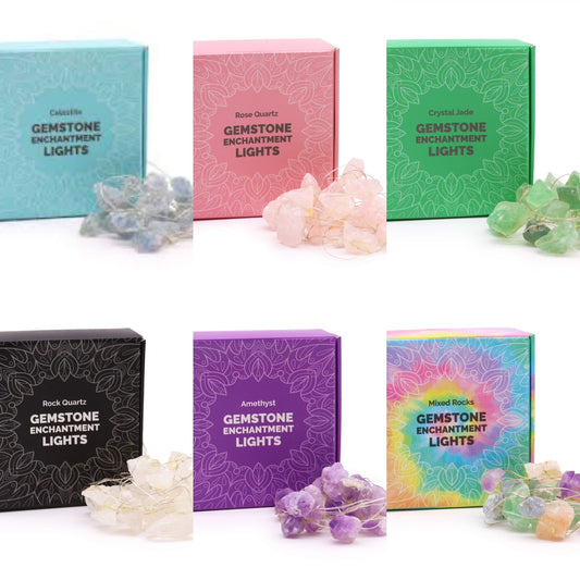 A collection of Gemstone Enchantment Rock Lights in various boxes, with the crystal rocks spilling out in front. Each box has a different color background and the lights are USB powered, indicated by the word 'Gemstone Lights' on the packaging.