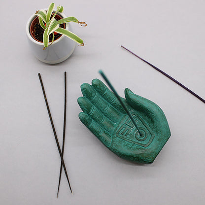 Green hand-shaped incense burner with incense stick with white background