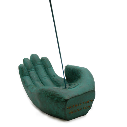 Green hand-shaped incense burner with incense stick with white background