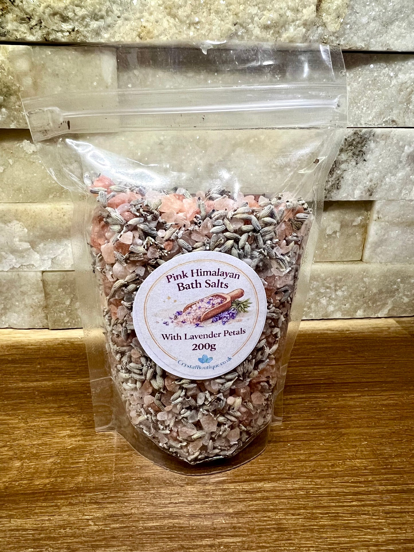 Bag of Pink Himalayan Bath Salts with Lavender Petals on a wooden surface