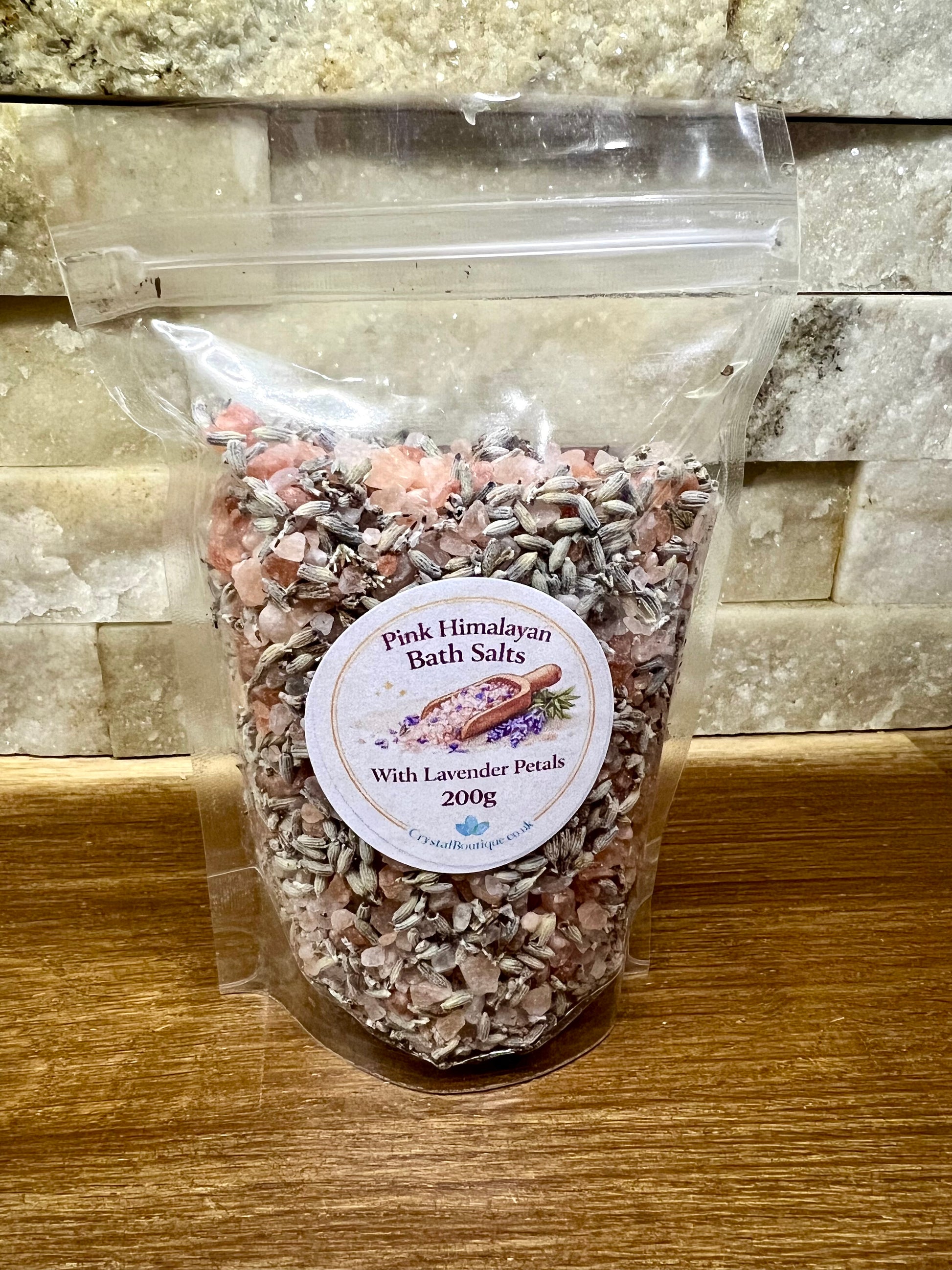 Bag of Pink Himalayan Bath Salts with Lavender Petals on a wooden surface