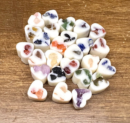 Heart-shaped soy wax melts with embedded crystal chips on a wooden surface