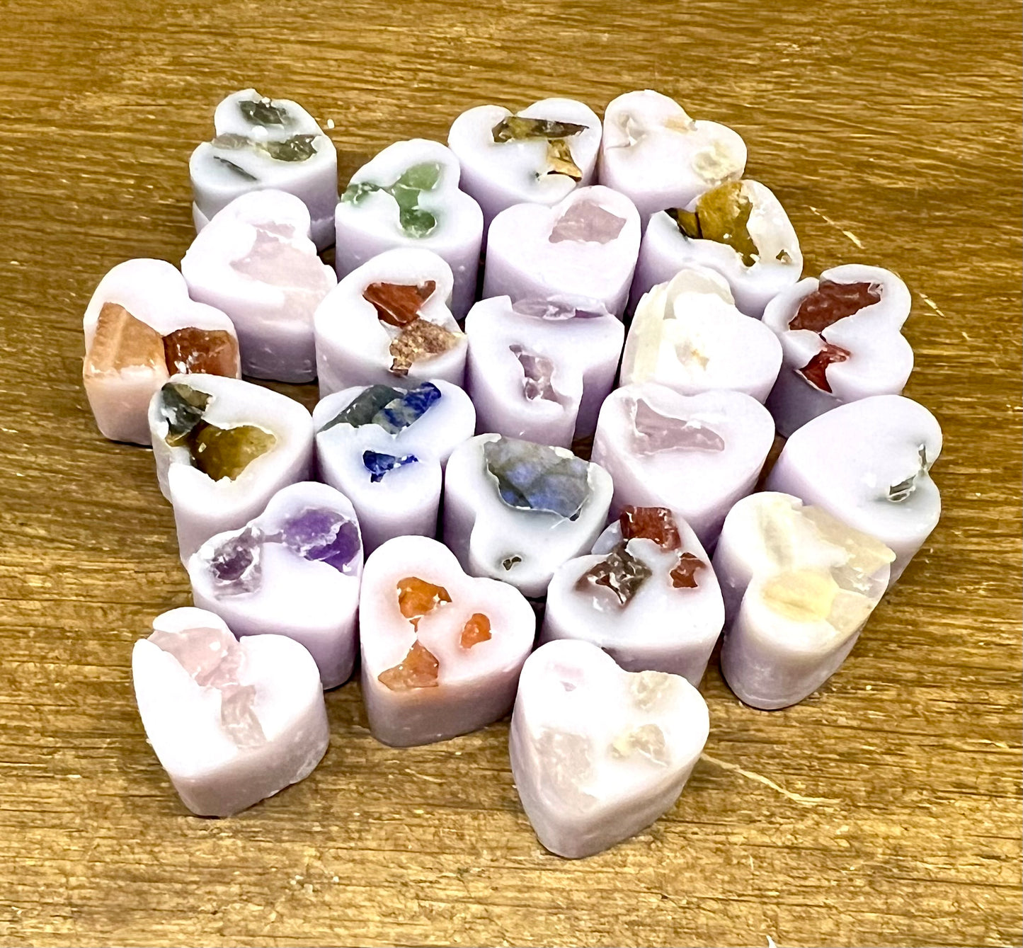 Heart-shaped soy wax melts with embedded crystal chips on a wooden surface