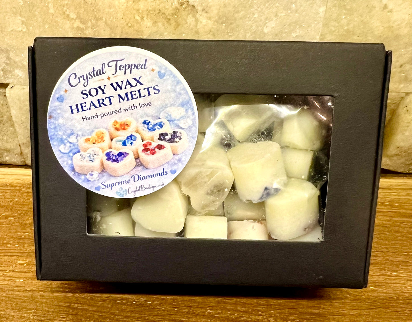 Box of crystal-topped soy wax heart melts with a label on a wooden surface.