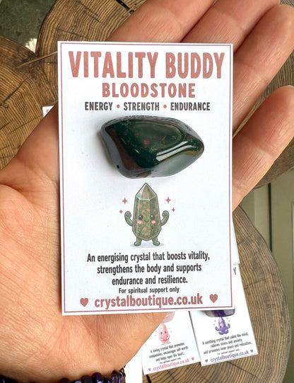 Hand holding a card with a bloodstone crystal and 'Vitality Buddy' branding.