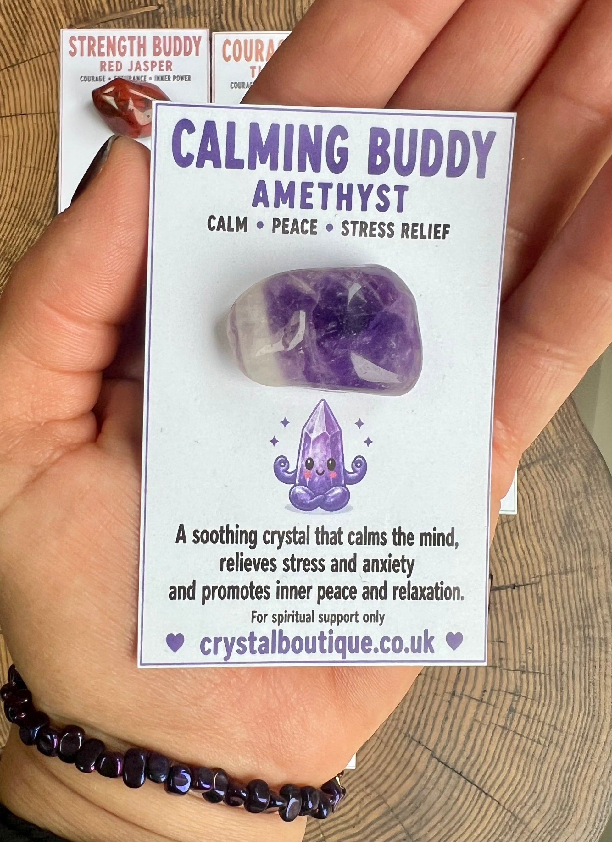 Amethyst crystal with 'Calming Buddy' packaging held by a hand