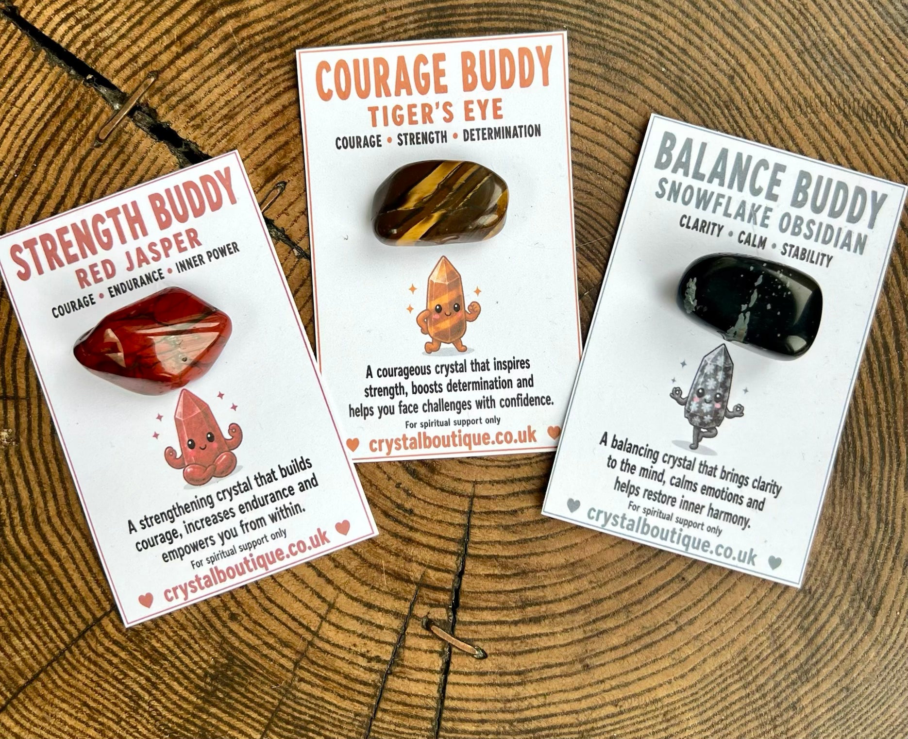 Three crystal stones with their packaging on a wooden surface