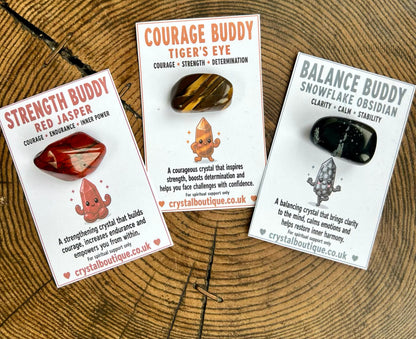 Three crystal stones with their packaging on a wooden surface
