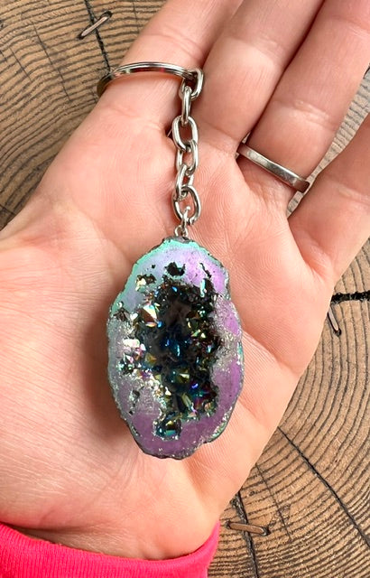 Rainbow aura quartz geode keyring shown in the hand for size