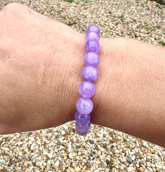 Amethyst lavender Purple beaded bracelet on a wrist with a pebbly ground background