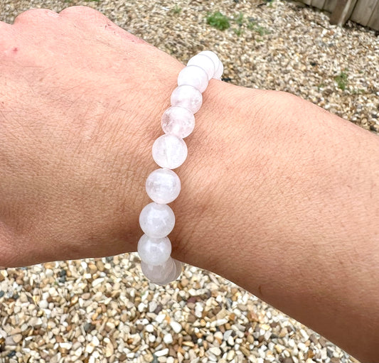 Hand wearing a light pink rose quartz crystal beaded bracelet on a wrist.