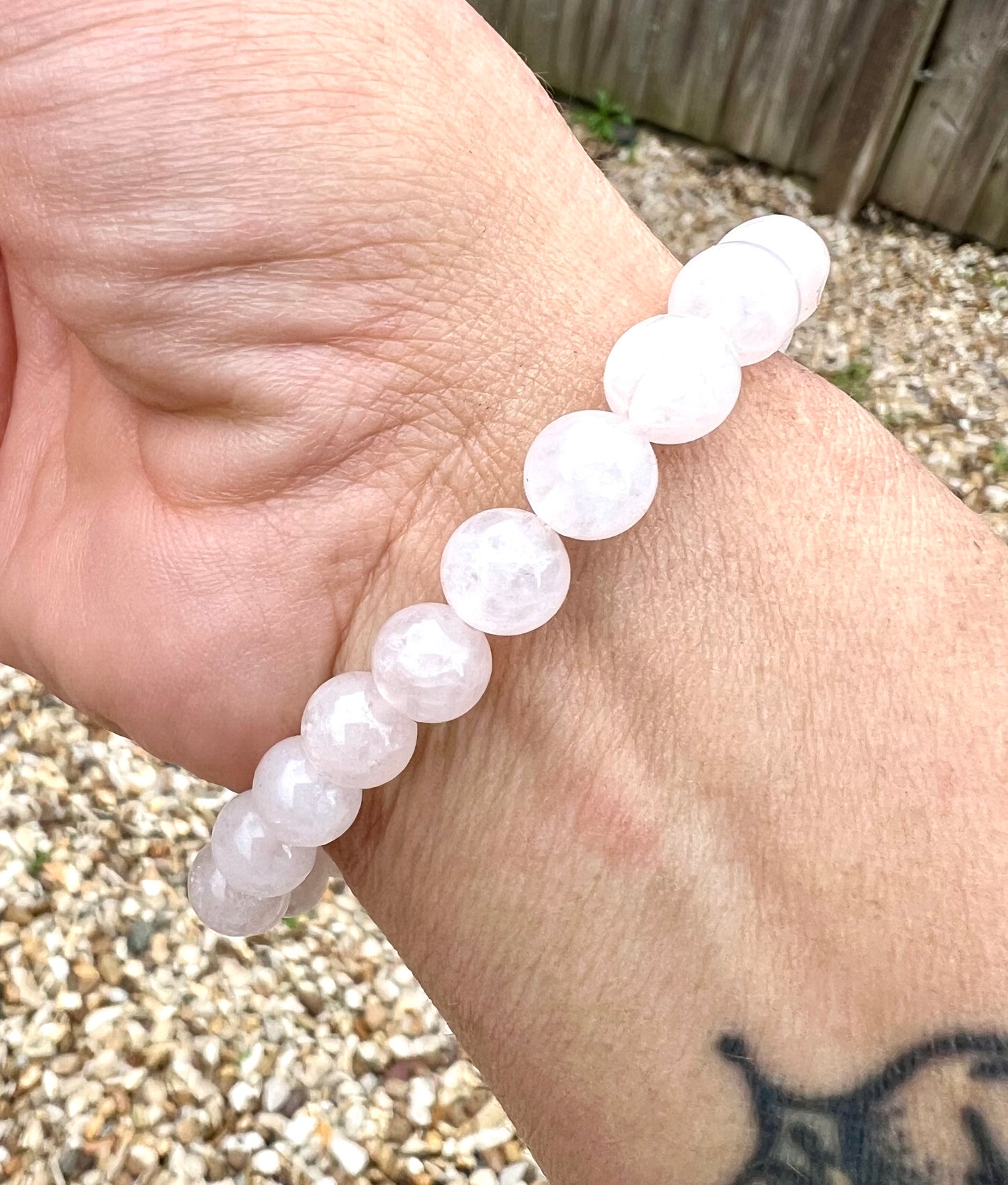 Hand wearing a light pink rose quartz crystal beaded bracelet on a wrist.