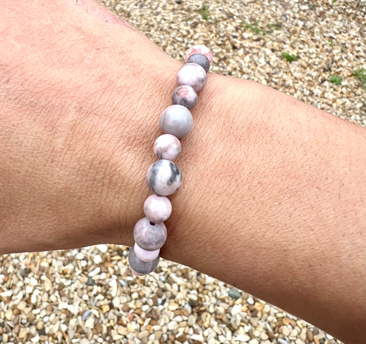 Beaded Zebra Jasper crystal bracelet on a wrist with a pebble background