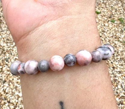Beaded Zebra Jasper crystal bracelet on a wrist with a pebble background