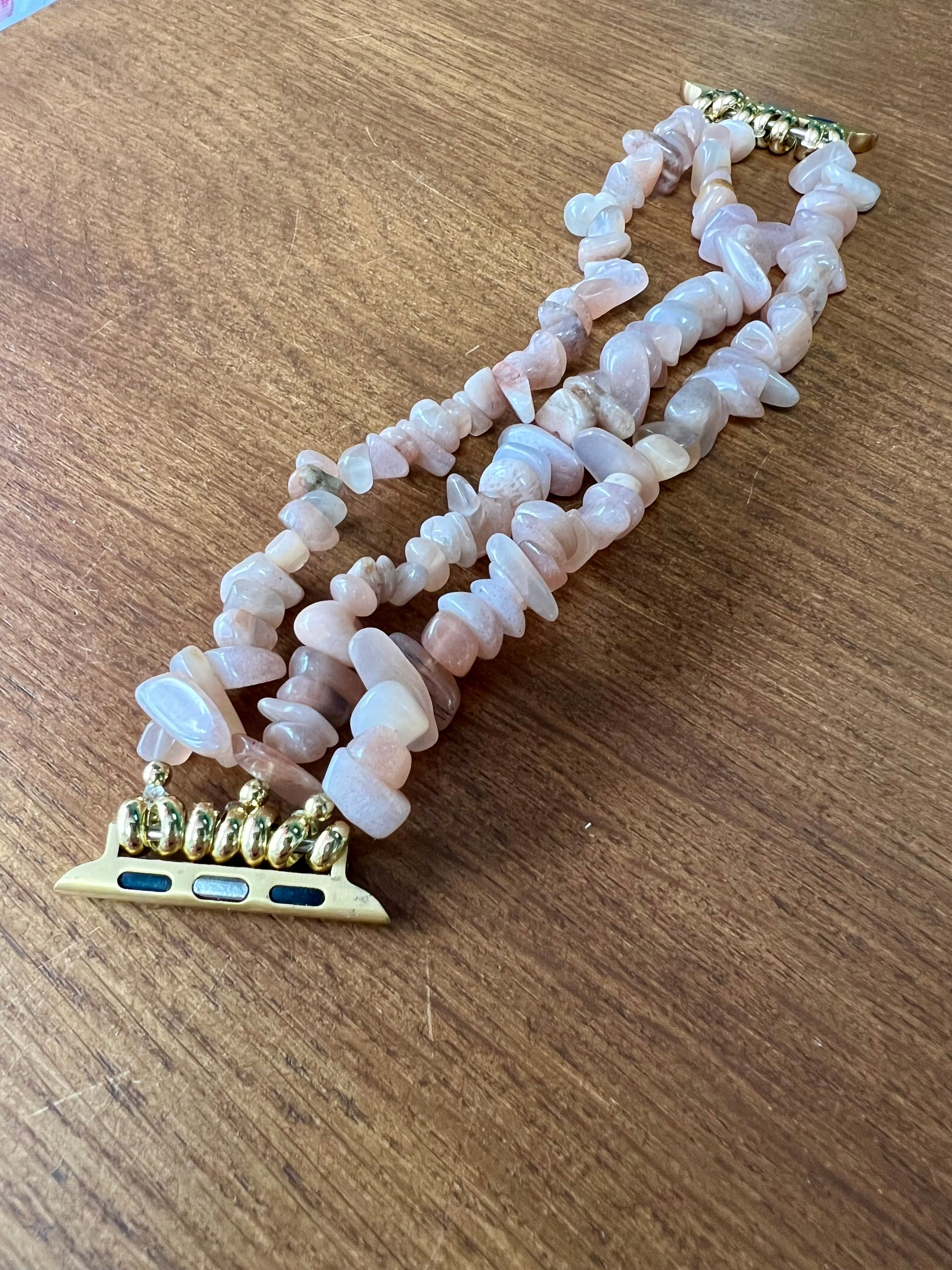 Peach Moonstone Crystal Apple watch strap with a gold band.