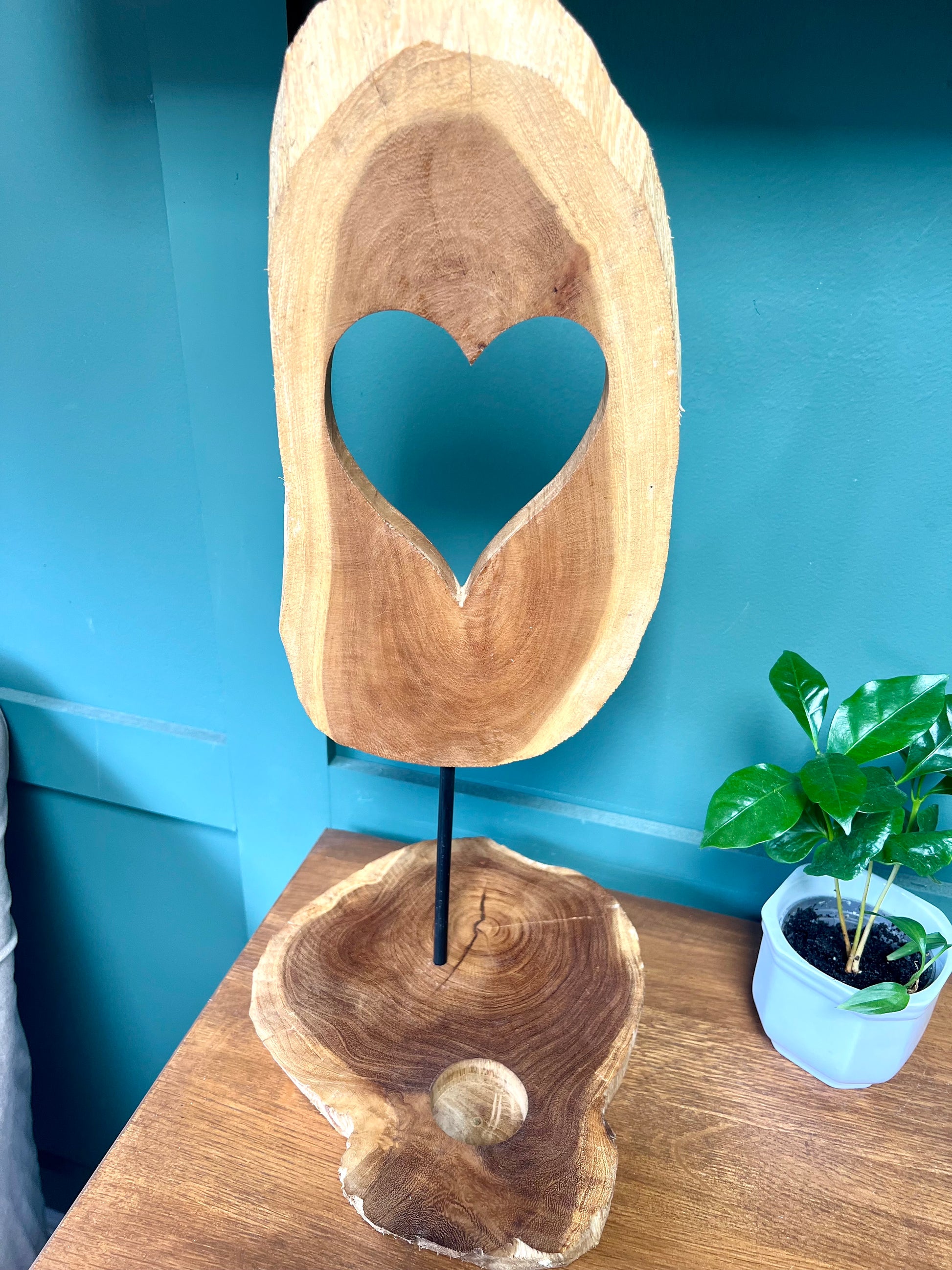 Wooden block with a heart cutout on a stand against a blue wall.